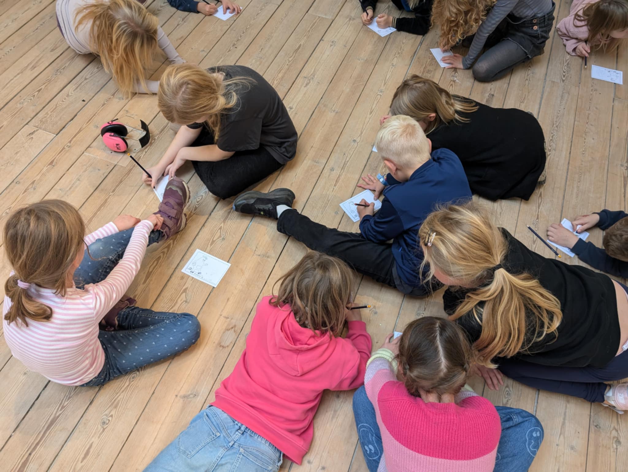 Elever sidder på gulvet og tegner dem selv på Bibber-postkort